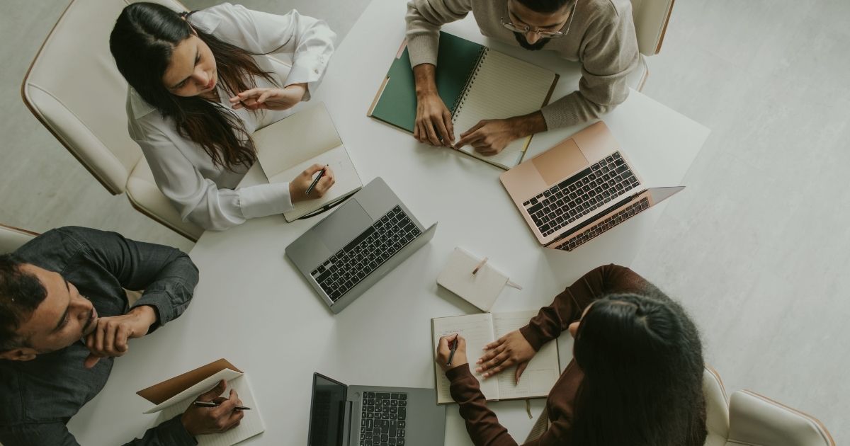 Energie im Team – Teammeeting von oben, bei dem alle konzentriert arbeiten und äußerlich alles funktioniert