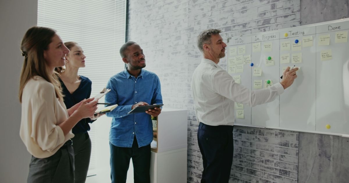 Rollen im Team klären – Team am Board, eine Person trägt bei, die anderen bringen sichtbar ihre eigenen Aufgaben ein